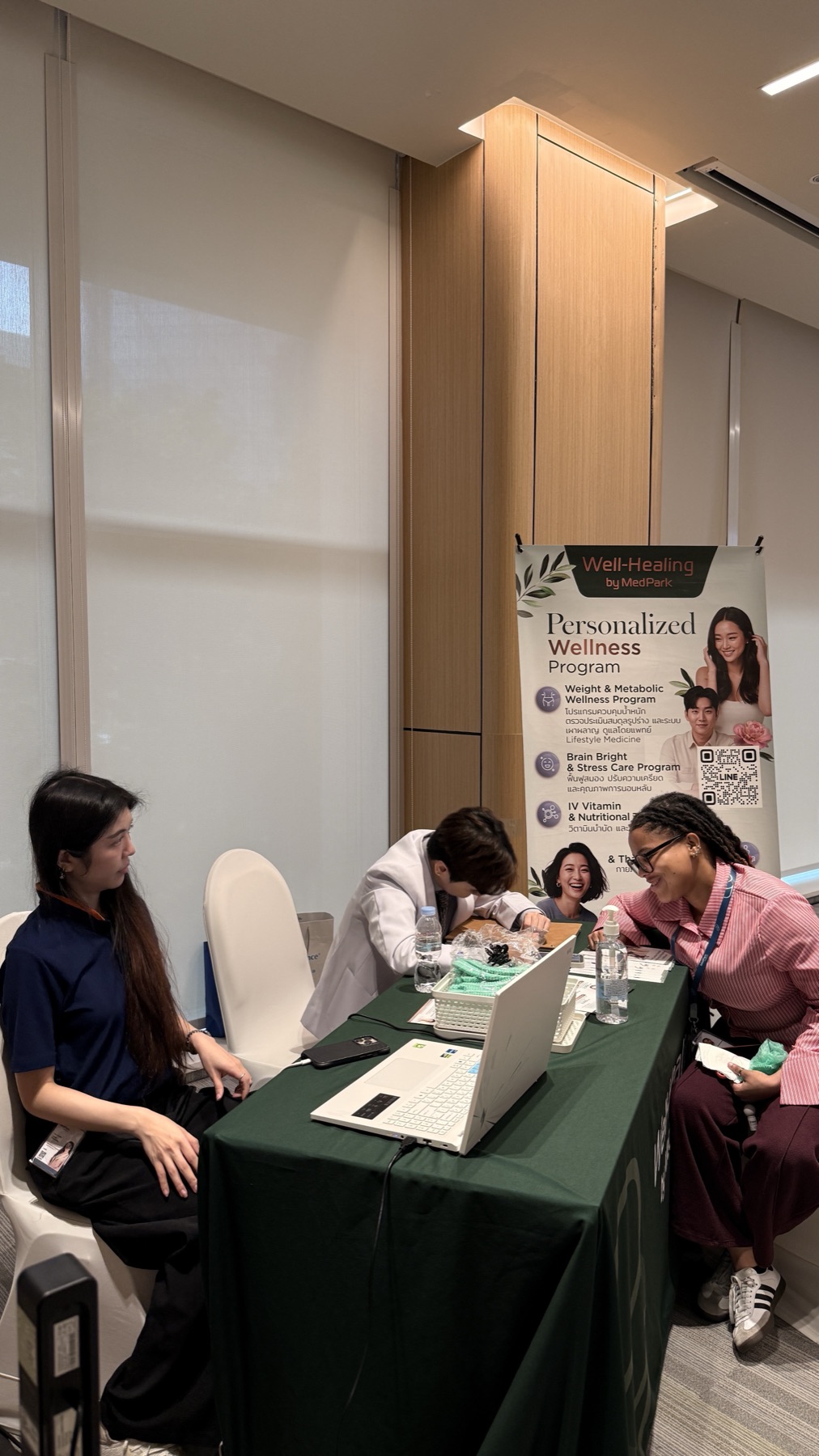 A wellness-programme sampling booth with a doctor consulting attendees at a table