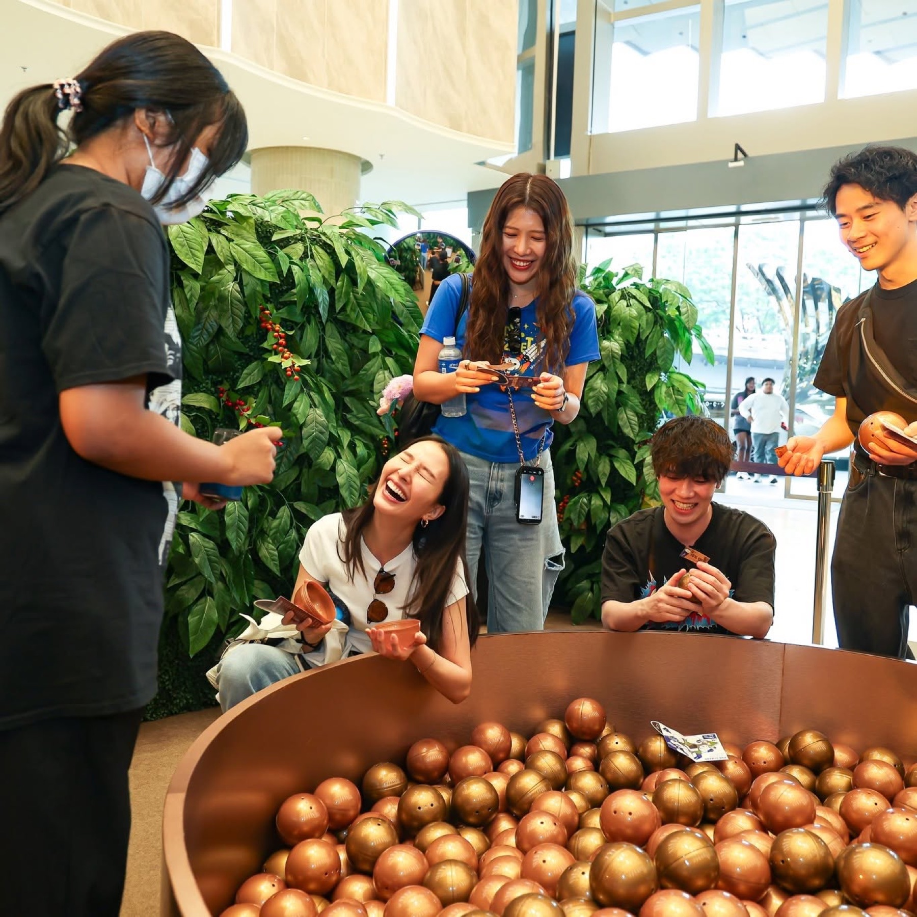 A group of young customers laughing over a promotional lucky-draw booth at an in-mall coffee brand activation